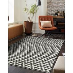 a black and white rug in a living room next to a chair with a plant on it