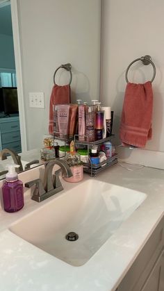 a bathroom sink with soap, lotion and other personal care items on it in front of a mirror