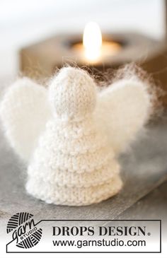 an angel figurine sitting on top of a table next to a lit candle