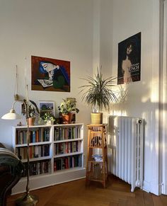 a living room with bookshelves, radiator and plants on the wall