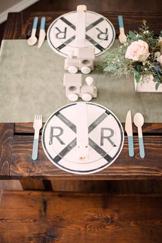 the table is set with white and blue plates, silverware, and flower centerpieces