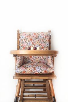 a wooden rocking chair sitting on top of a white wall