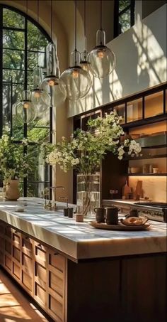 a large kitchen with lots of counter space and hanging glass vases filled with flowers