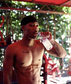 a shirtless man drinking water from a bottle