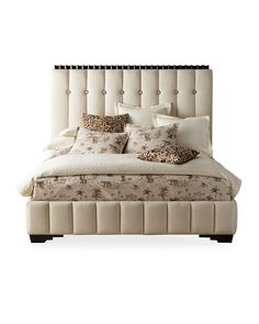 a bed with lots of pillows on it and a headboard made out of upholstered fabric