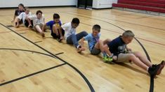 a group of children sitting on the floor playing with a soccer ball in a gym