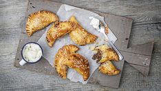 some pastries are sitting on a tray next to a bowl of cream and a spoon