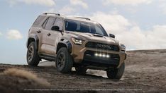 the front end of a tan toyota truck driving on dirt