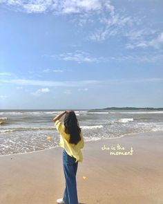 a woman standing on top of a beach next to the ocean