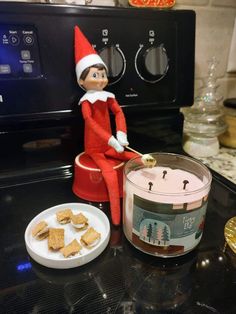 an elf is sitting on top of the stove with crackers in front of it