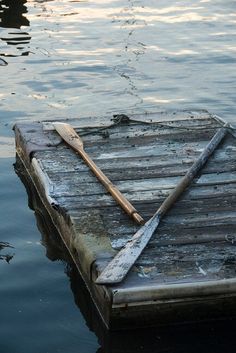 an old wooden dock in the middle of water with a paddle sticking out of it