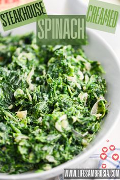 a white bowl filled with spinach on top of a table