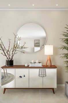 a living room with a mirror, plant and lamp on the sideboard in front of it