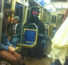 a man in a black mask sitting on a train with red eyes and a ghost like head