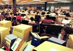 an office filled with people sitting at desks and working on computer screens in front of them