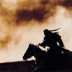 a man riding on the back of a white horse next to a brown and black cloud