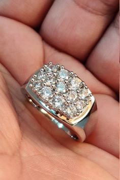 a person is holding a ring with diamonds on it in their hand and there are two fingers that hold the ring