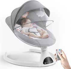 a person holding a remote control in front of a baby's bouncer chair