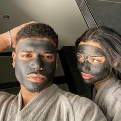 a man and woman with facial masks on their faces posing for a photo in front of a mirror