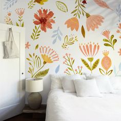 a white bed sitting in a bedroom next to a wall with flowers painted on it