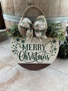 a merry christmas sign hanging from the side of a barrel with two bows on it