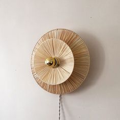 a wall clock made out of bamboo sticks with a gold ball on the front and side