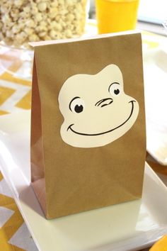 a brown paper bag with a monkey face on it sitting on top of a white plate