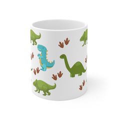 a white mug with green and blue dinosaurs on it