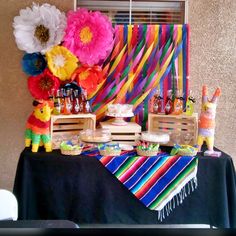 a table topped with lots of colorful paper flowers and candy bar wrappers on top of it