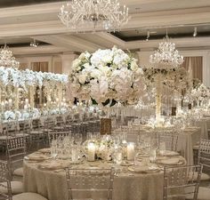 an elegant wedding reception with chandeliers and white flowers in the centerpieces