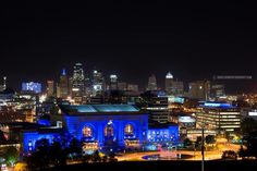 the city skyline is lit up at night with blue lights in the foreground and skyscrapers