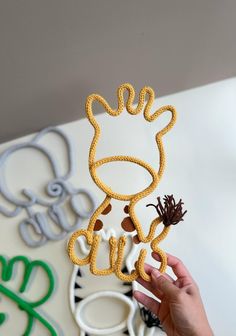 a hand holding up a piece of string art that looks like a giraffe