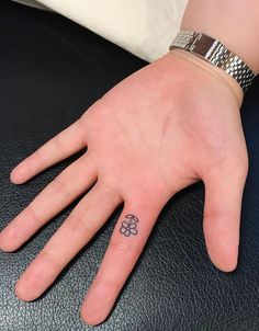 a person's hand with a small flower tattoo on the middle of their finger