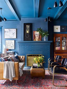 a living room filled with furniture and a fire place in front of a blue wall