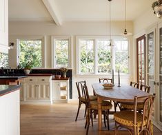 a dining room table surrounded by chairs and windows