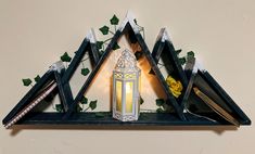 a decorative shelf with a lit candle and some books on it's sides in front of a wall