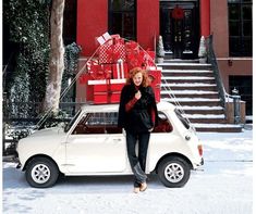 a woman standing in front of a car with presents on the roof and back door