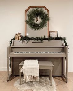 a christmas wreath on top of a piano in front of a mirror with a wreath