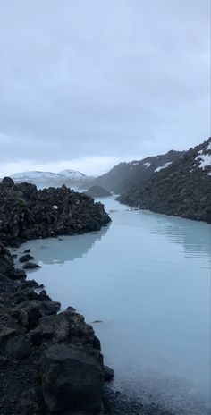 a body of water surrounded by rocks and snow