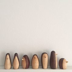 five wooden pegs lined up in a row on top of a white shelf next to a wall