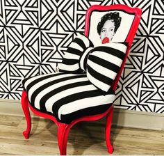 a red chair with a black and white striped bow on it's back sitting in front of a wall