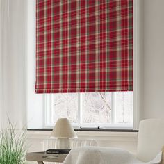 a red and white plaid roman blind in a living room with a chair, coffee table and lamp