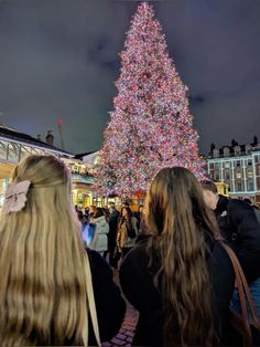 people standing in front of a large christmas tree