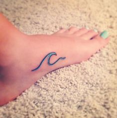 a woman's foot with a wave tattoo on it