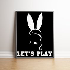 a black and white poster with the words let's play on it in front of a wooden floor