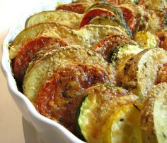 a white dish filled with cooked zucchini and tomatoes