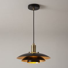 a black and gold pendant light hanging from the ceiling in a room with white walls