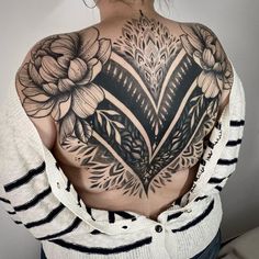 the back of a woman's upper half with flowers and leaves on her chest