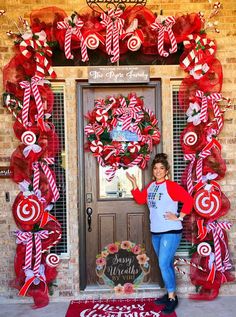 a woman standing in front of a door decorated with red and white candy canes