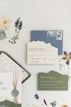 the wedding stationery is laid out on top of the table with flowers and other items